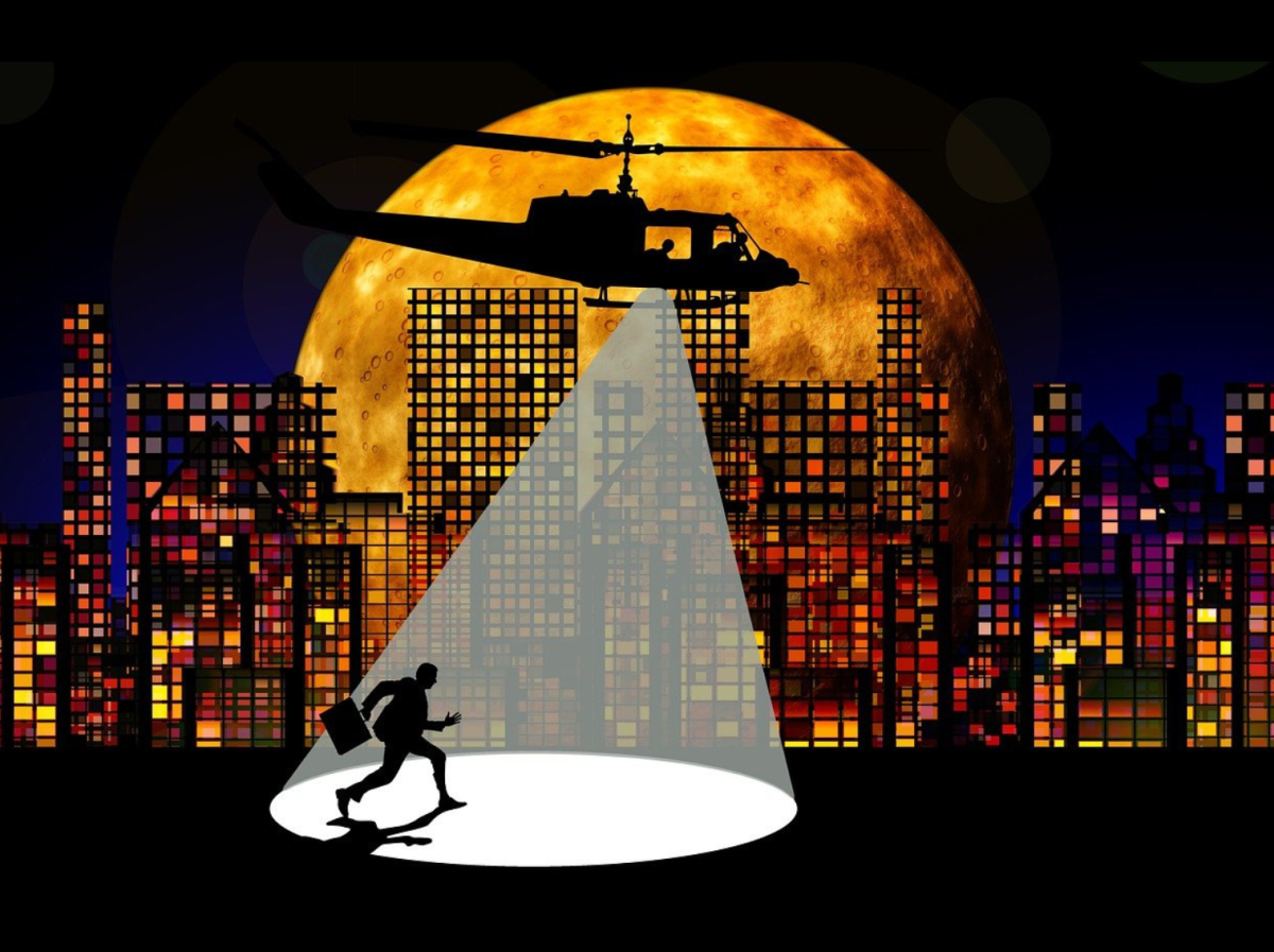 cityscape at night with helicopter spotlighting a silhouette of an implied criminal creeping by